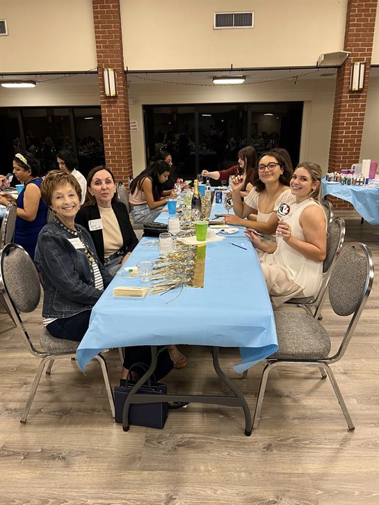 Friends gather around a table decorated for a festive celebration, sharing laughter and drinks.