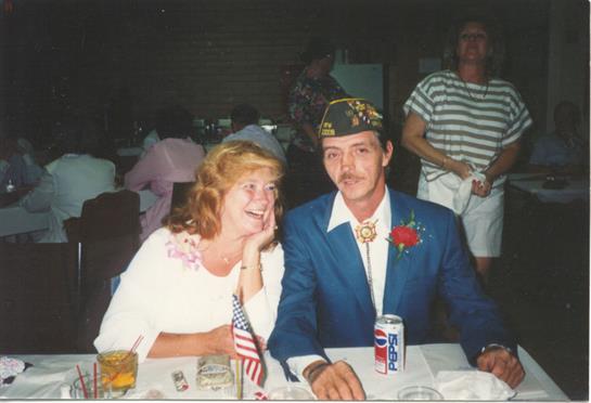 A couple shares a joyful moment while dressed in formal attire at a lively celebration.