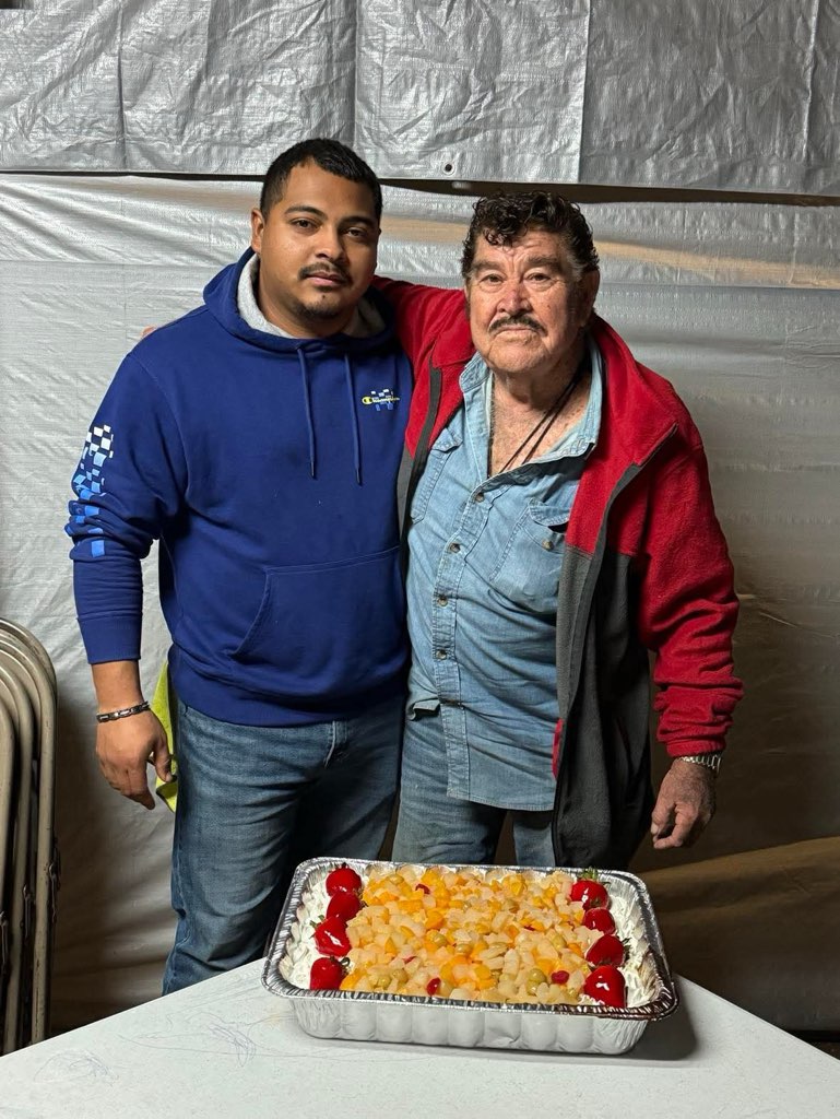 Two men standing next to a cake