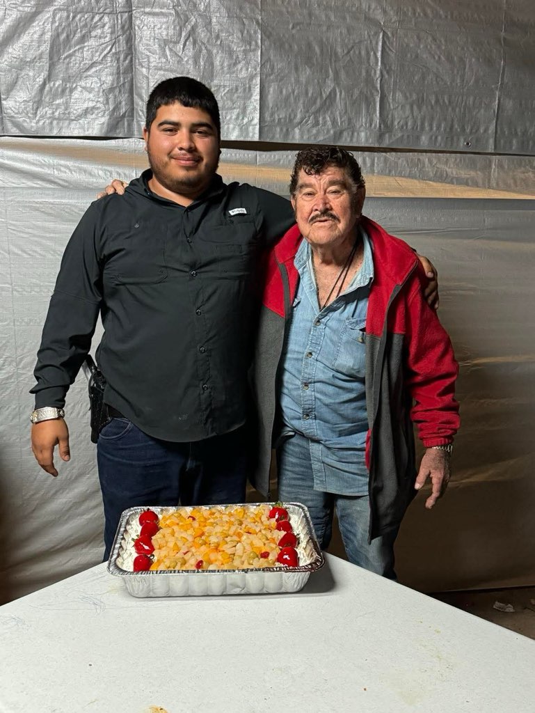 Two men standing next to a tray of food