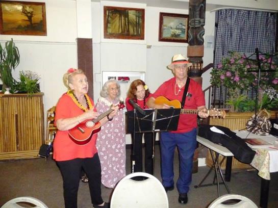 Four musicians engage the audience with lively songs in a warm, inviting setting.