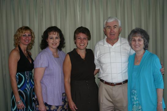 Five individuals are posing together with smiles at a family gathering indoors.