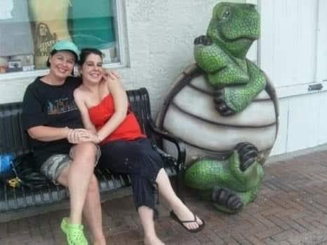 Two women sitting on a bench next to a statue