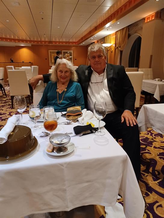 A couple sits at a beautifully set table enjoying dinner in a formal restaurant setting.