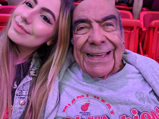 Two enthusiastic fans share a joyful selfie during a basketball game at the arena.