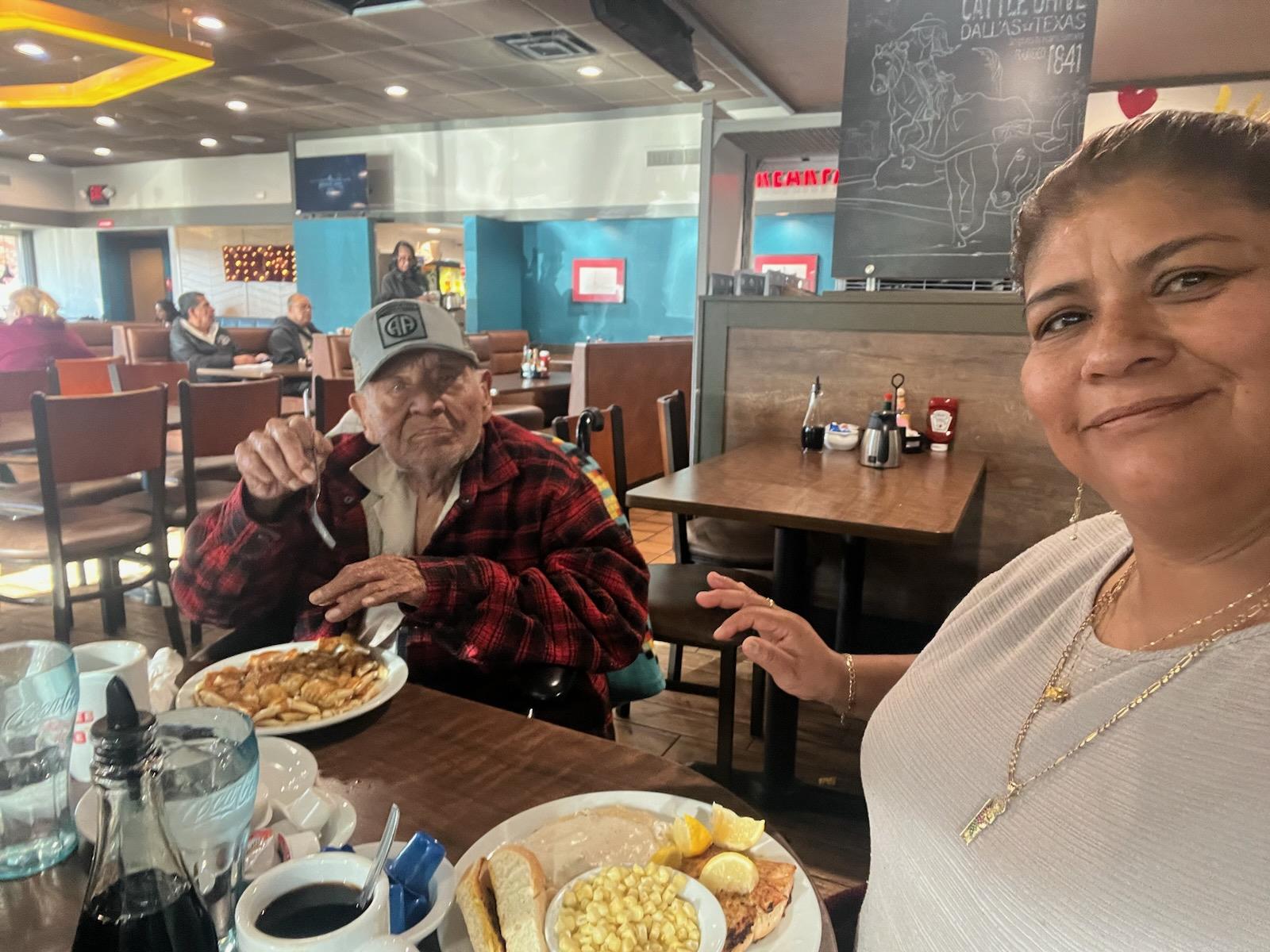 Two friends share a joyful breakfast in a busy diner, enjoying pancakes and coffee.