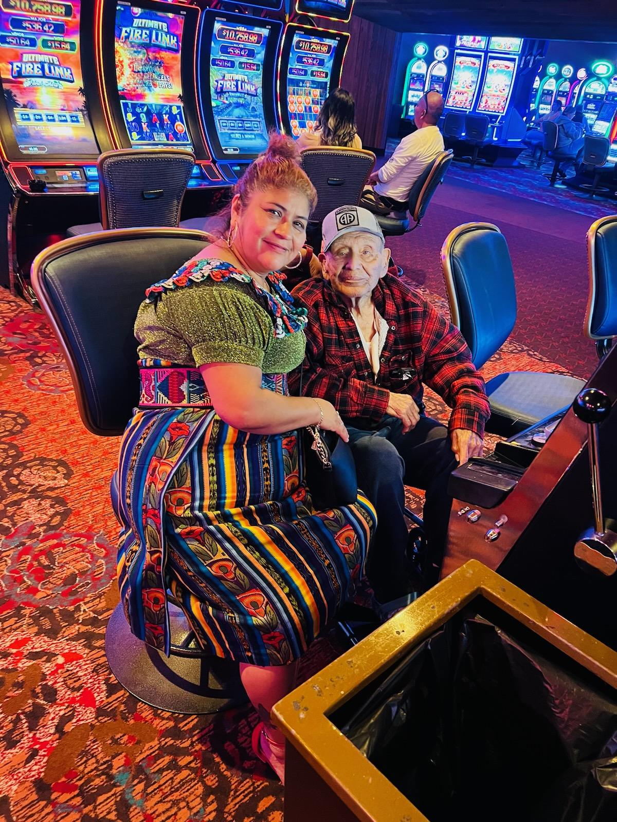 A couple sits comfortably at a slot machine, sharing smiles and enjoying their time together.
