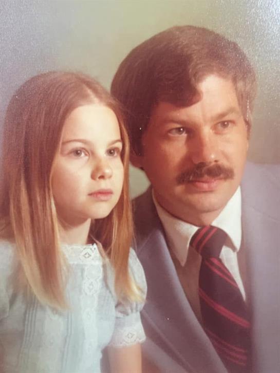 A father and daughter pose together, showcasing a loving bond and 1970s fashion.