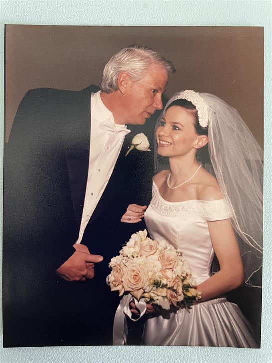 A newly married couple smiles at each other, surrounded by love and celebration at their wedding.