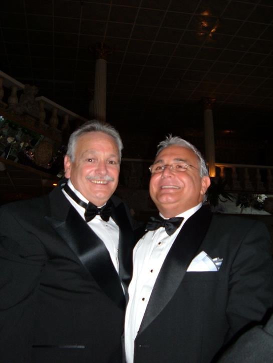 Two well-dressed men smile together, enjoying the festive celebration.