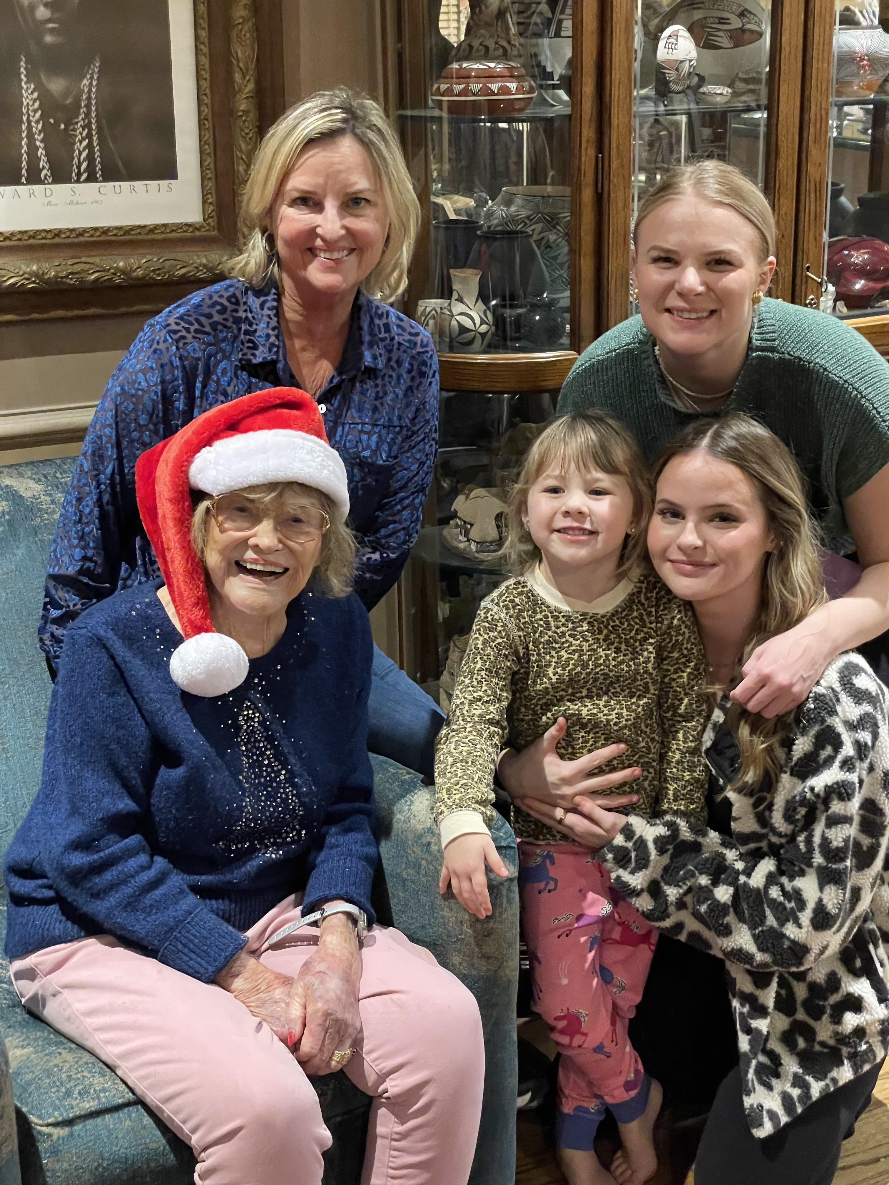 Four generations of family members pose together, enjoying a festive holiday moment.