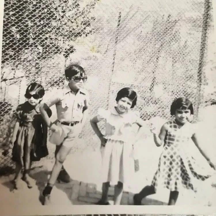 Group of four children enjoying their time in a park, showcasing playful poses and smiles.