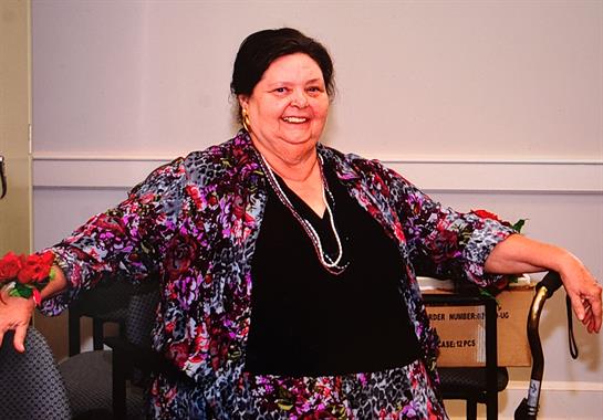 A cheerful woman dressed in bright colors poses, showcasing her personality and style.