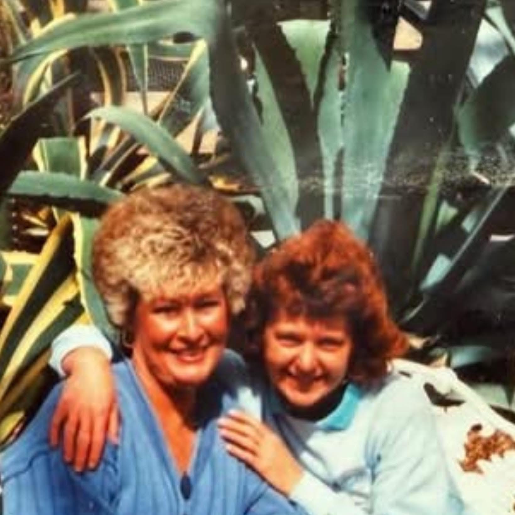 Two friends are enjoying a joyful moment outdoors surrounded by lush greenery.