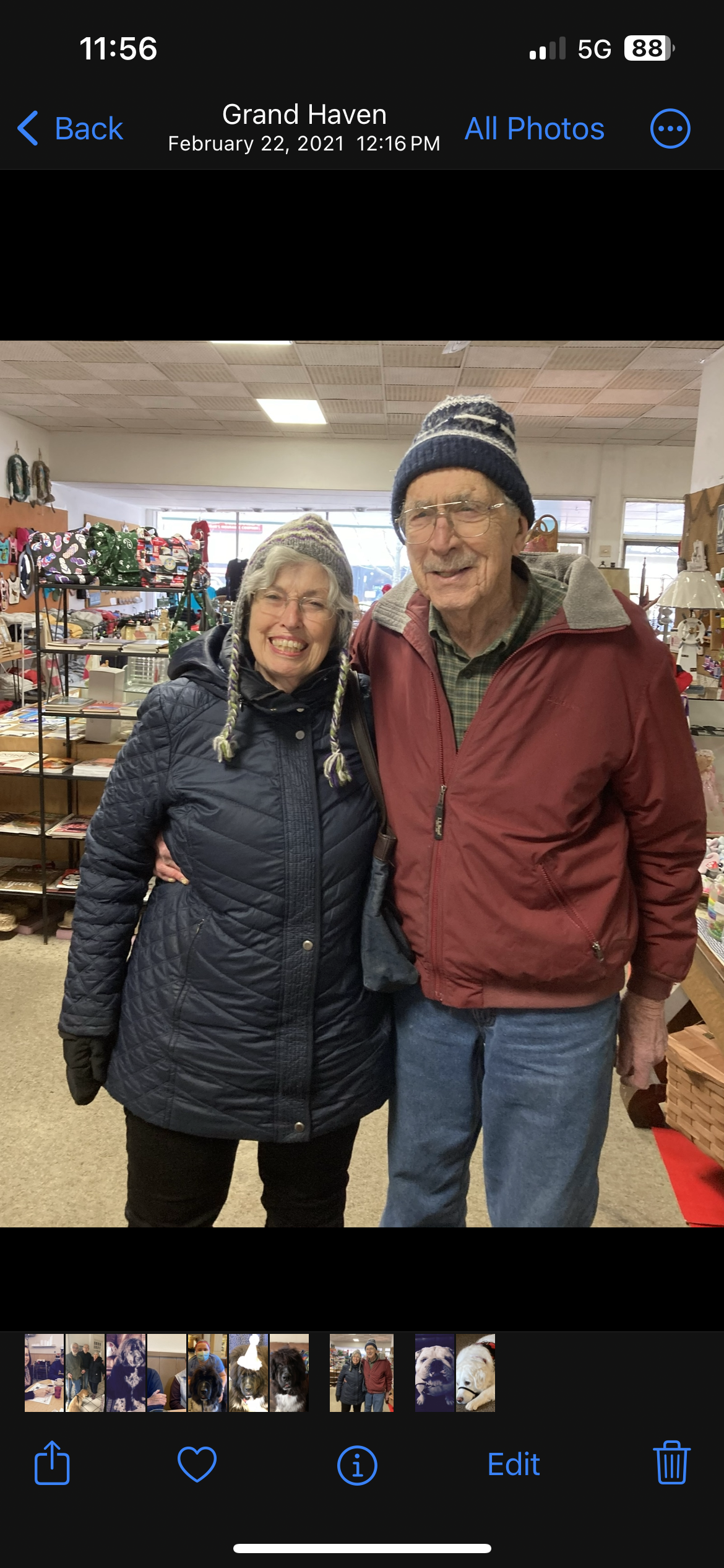 A couple stands together, smiling warmly while exploring a local market filled with various items.