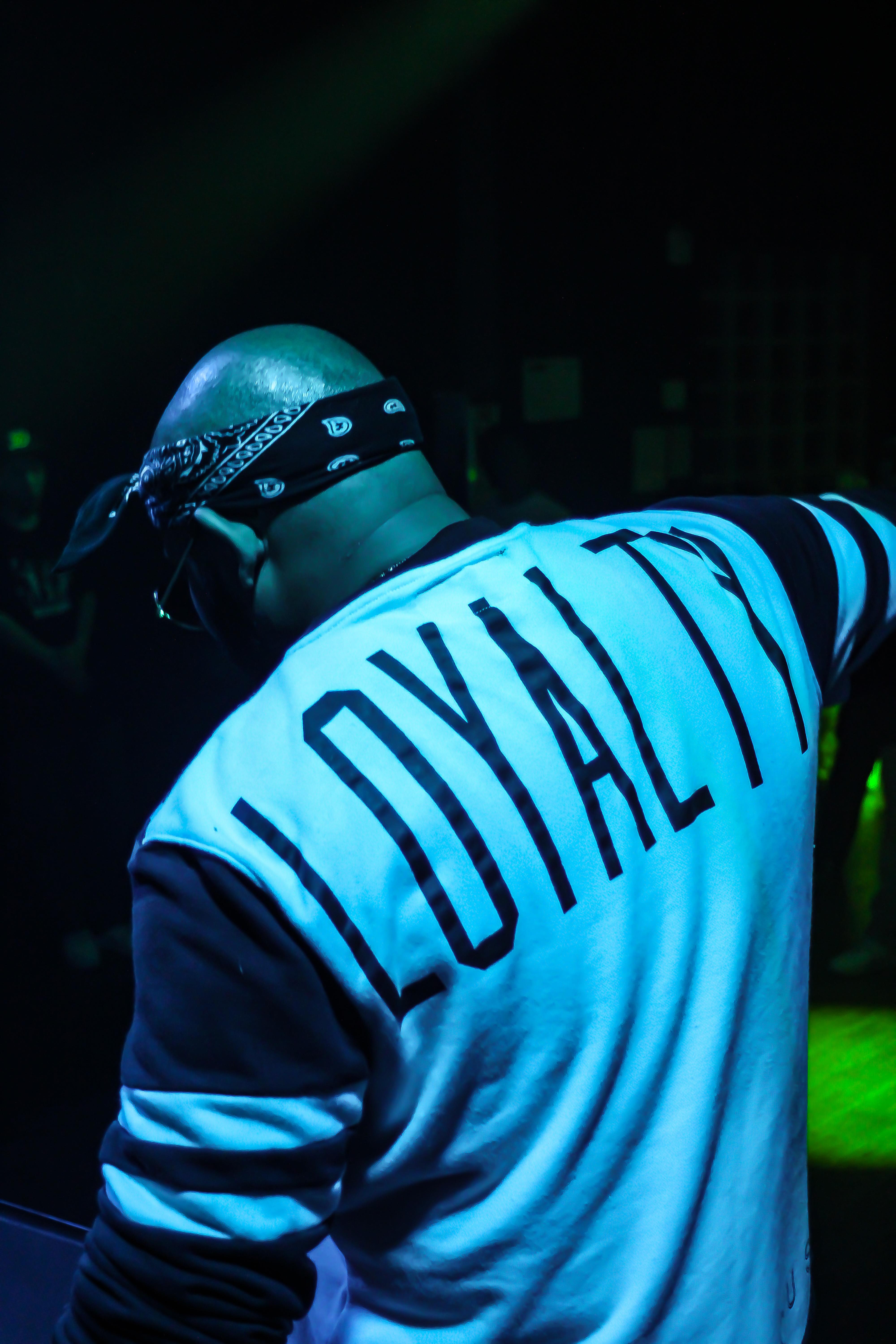 A performer engages the crowd while wearing a stylish shirt at a lively nightclub setting.