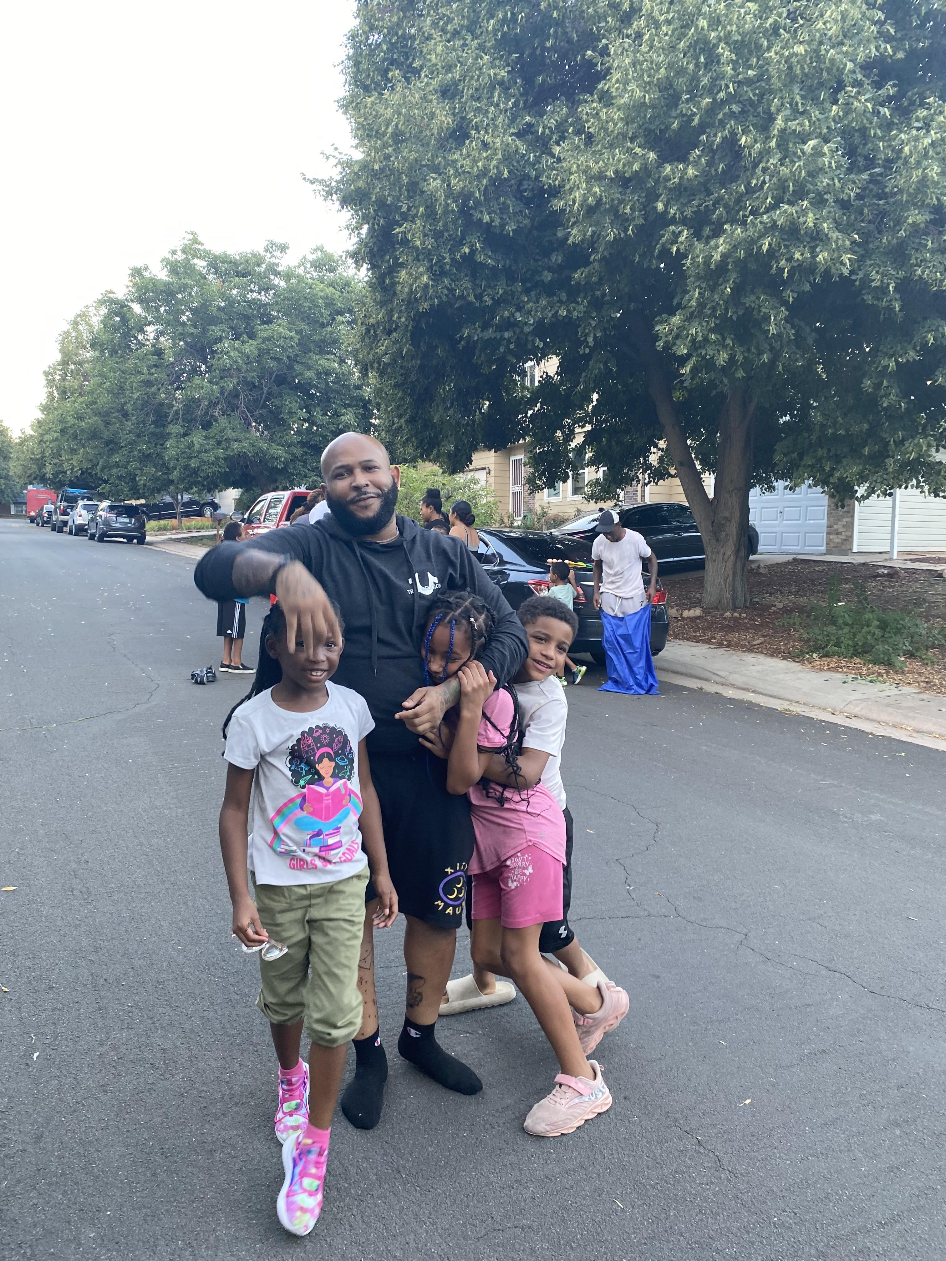 A man enjoys quality time with two children while others engage nearby during a warm day.