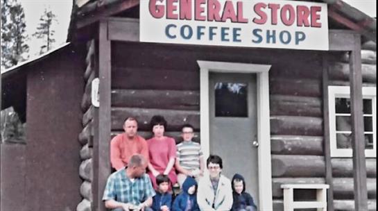 A group of people sitting on a porch of a log cabin
