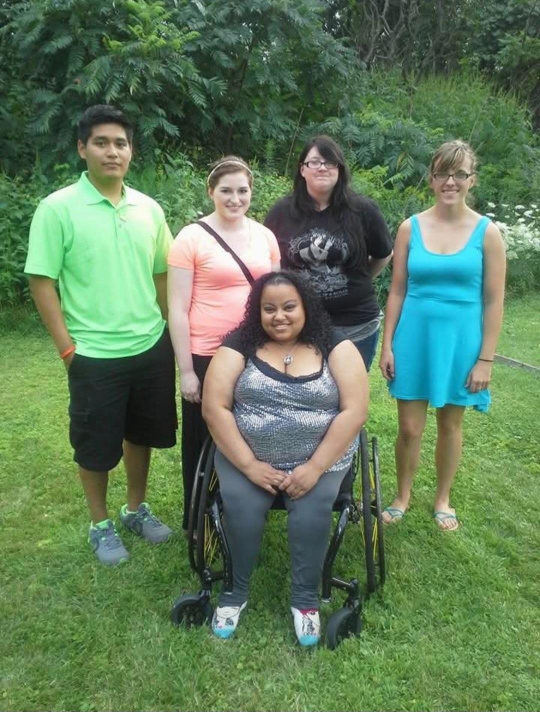 A diverse group of friends poses together in a lush park, enjoying their time outdoors.