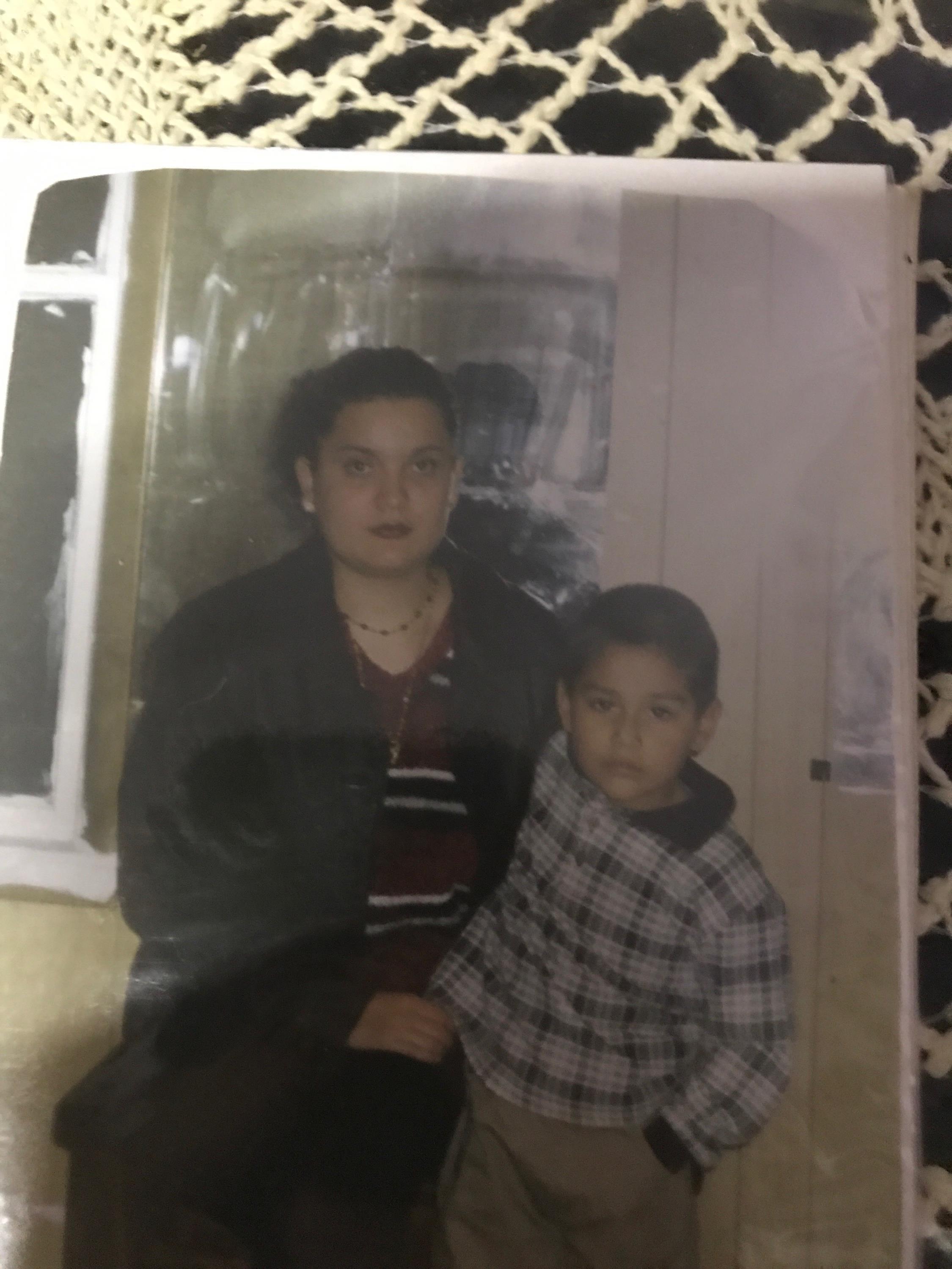 A woman and a young boy pose together indoors, showcasing a warm family moment.