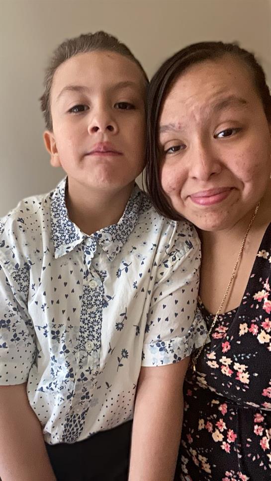 A mother and her son pose closely for a photo, both smiling and enjoying the moment together.