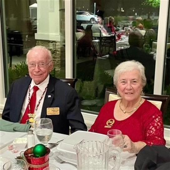 Elderly couple dressed elegantly attends a festive dinner in a cheerful atmosphere.