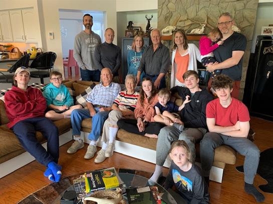 A large family enjoys each other's company, smiling and posing together in a warm living room.