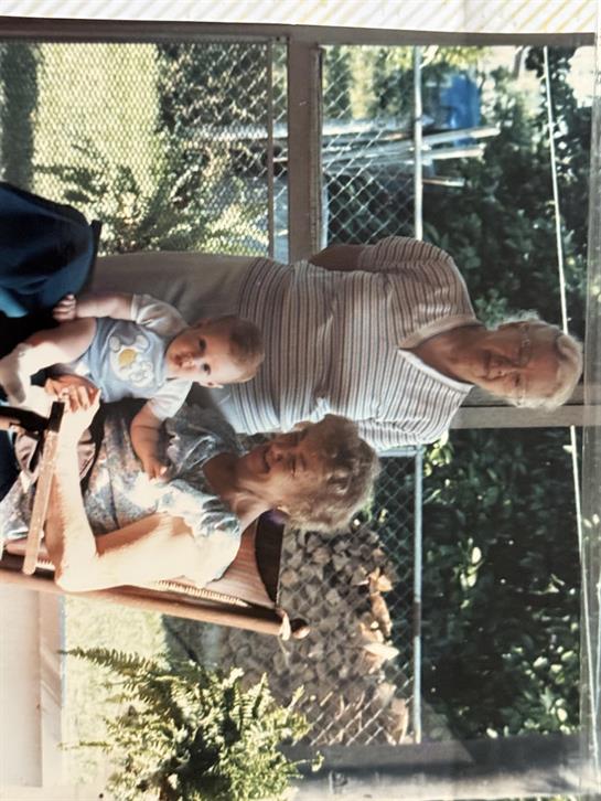 Family members gather in a bright garden, enjoying each other's company on a warm day.