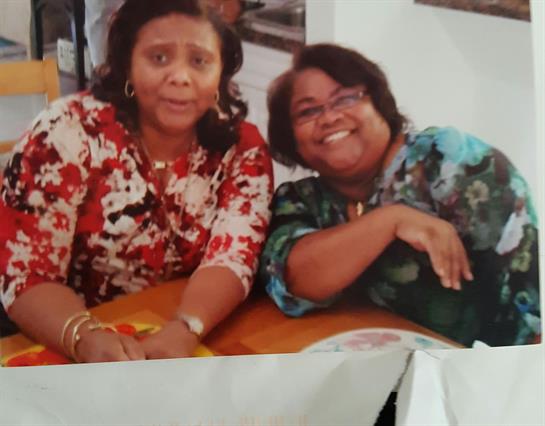 Two women enjoying a cheerful moment together at a social gathering, sitting at a table.