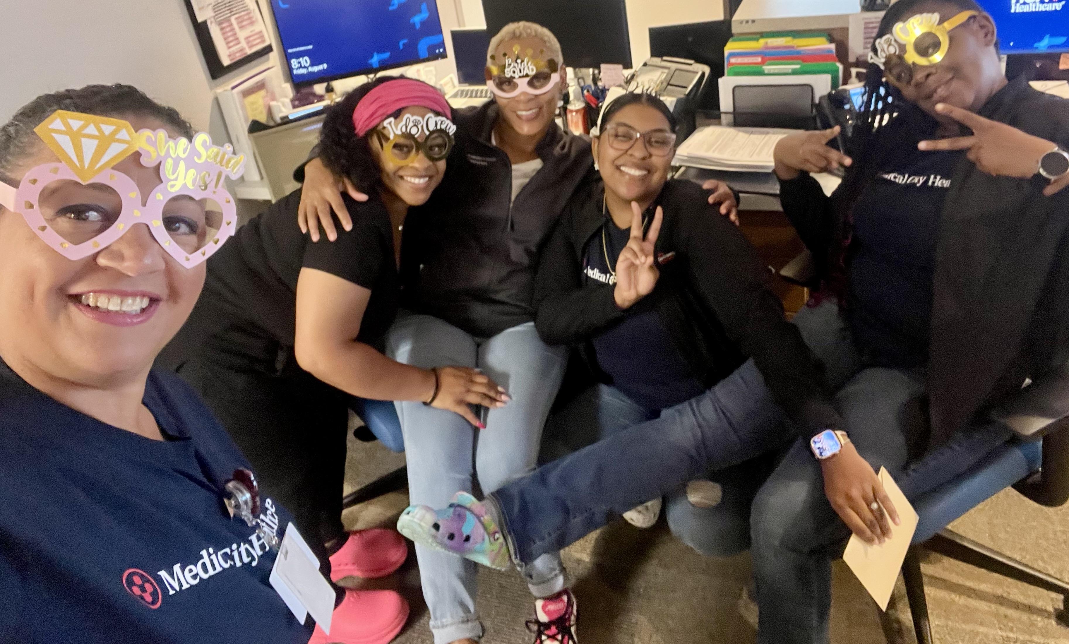 Friends gather in an office, wearing colorful accessories and sharing smiles during their break.