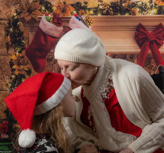 A woman kissing a child in a hat