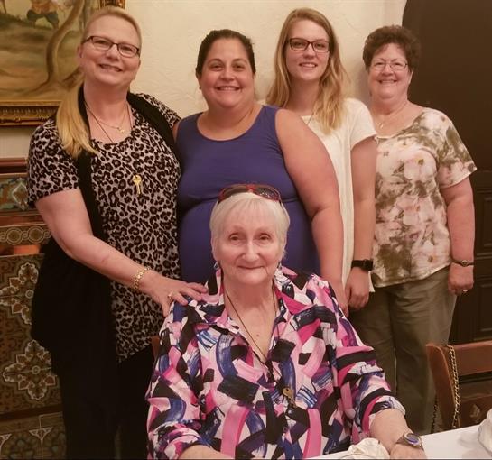 A group of five women shares happiness and laughter at a restaurant table during dinner.