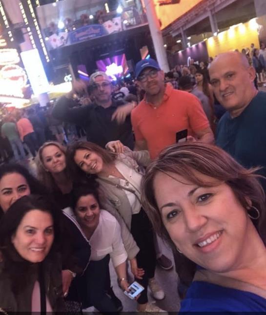 A group of smiling friends gathers for a joyful selfie during a vibrant city night.