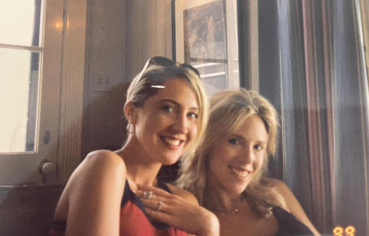 Two friends smile warmly while seated comfortably, capturing a moment of joy together.