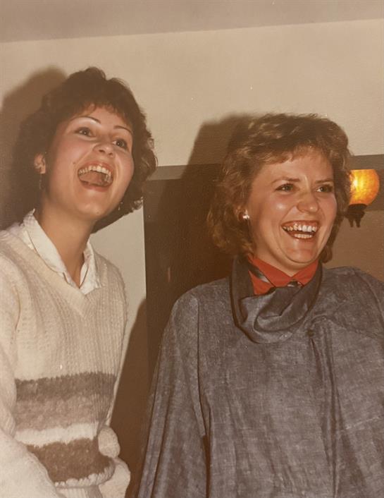 Laughter fills the room as two women share a happy moment at a social gathering.