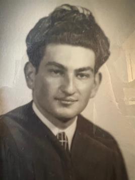 A well-dressed young man smiles confidently in a formal setting.