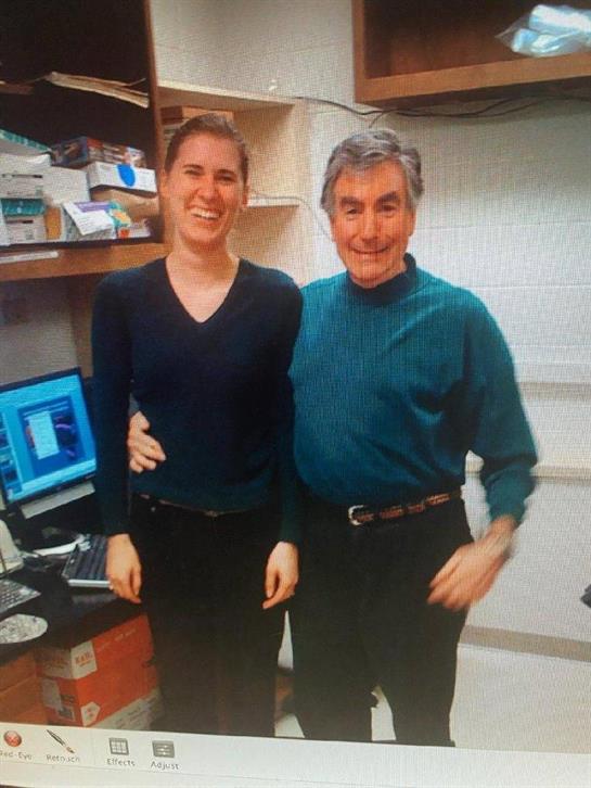 Two people stand closely together, smiling joyfully in a bright office setting.