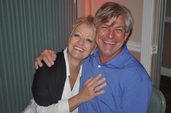A couple shares laughter and happiness while embracing during a social event.