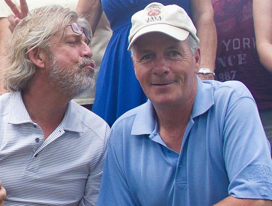 Two men enjoy a cheerful moment together during a summer gathering, showcasing friendship.