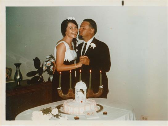 A man and woman kissing in front of a cake