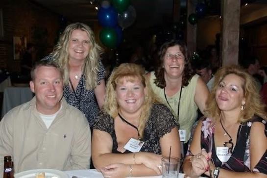 Friends smile and pose together at a festive gathering in a lively setting, having a great time.