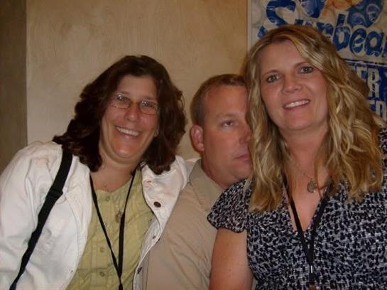 Three friends smile together in a relaxed atmosphere during a social event, highlighting fun