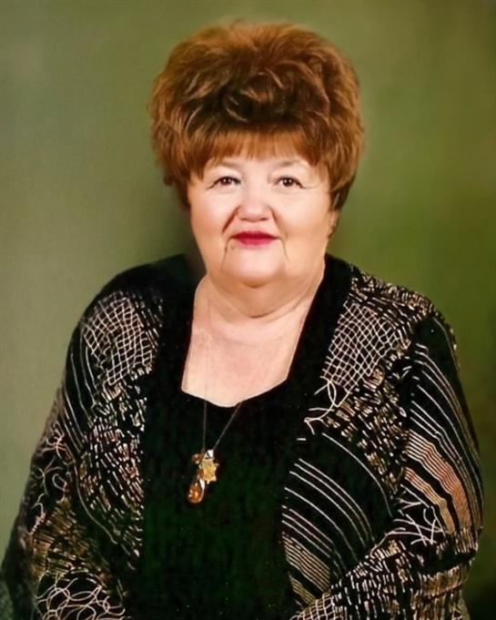 Elderly woman smiles while dressed elegantly in a black outfit with stylish shawl.