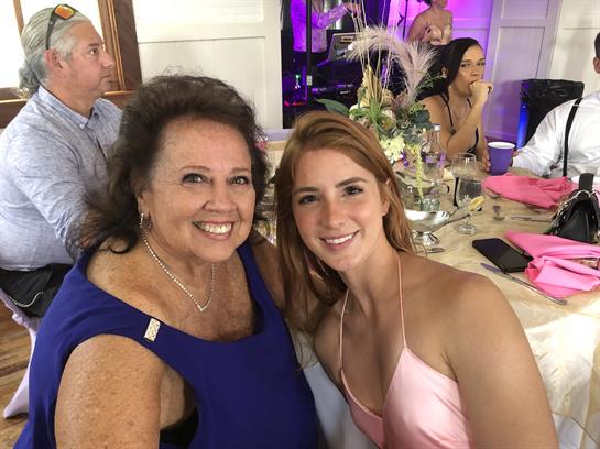 Two women enjoy a joyful moment together at a festive gathering surrounded by friends.