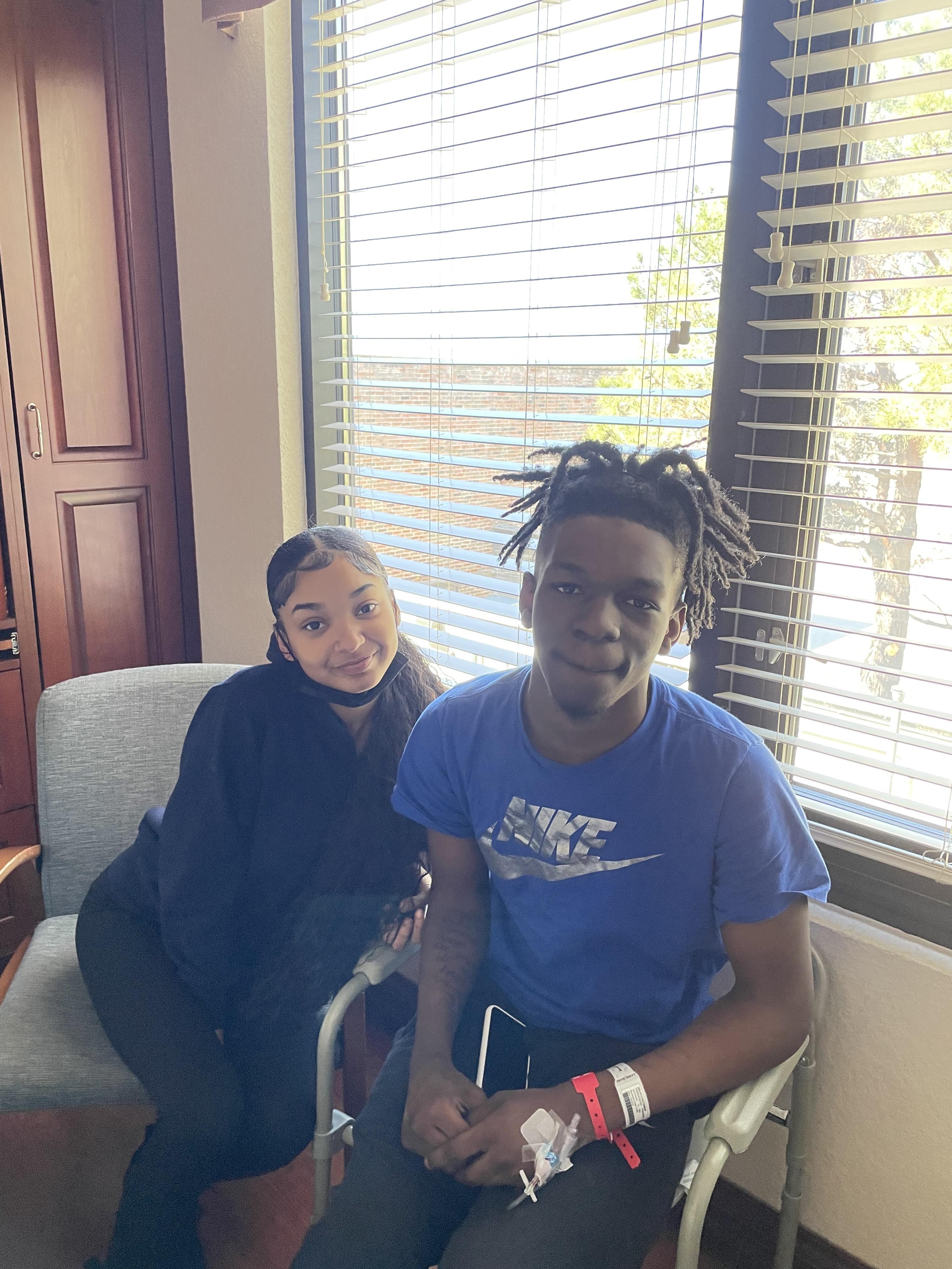 A young couple sits together in a bright room, enjoying each other's company and smiling.