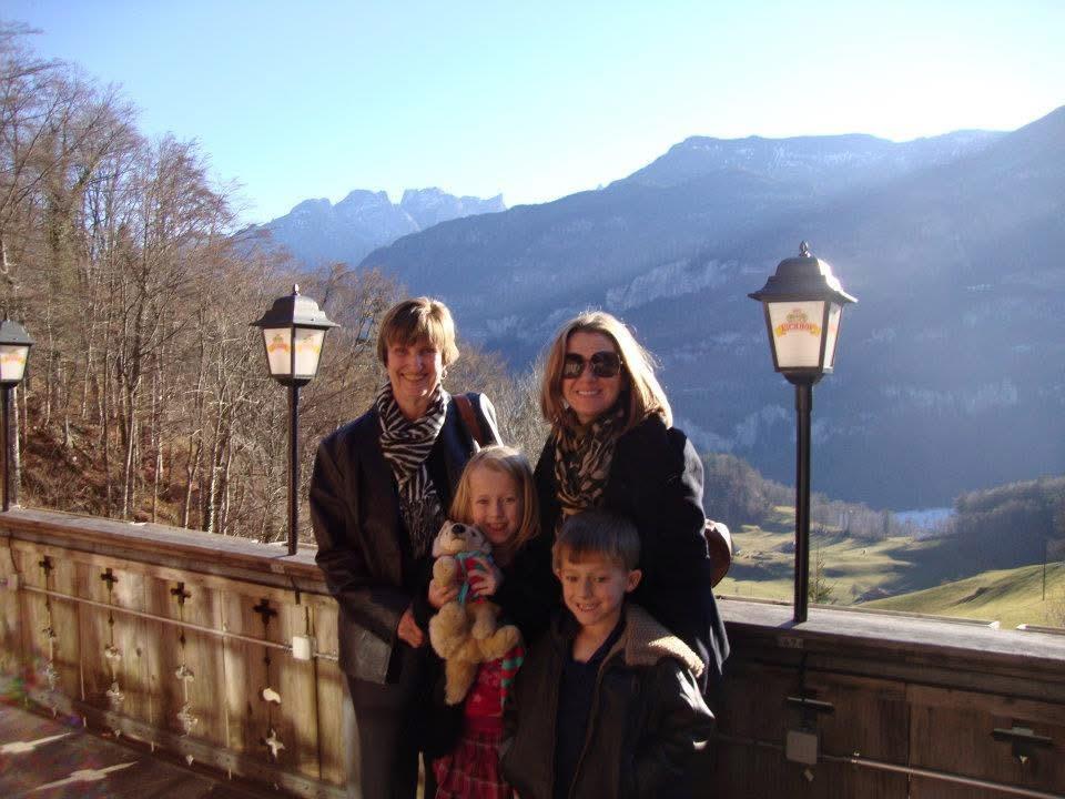 A joyful family poses for a picture amidst majestic mountains on a sunny day.