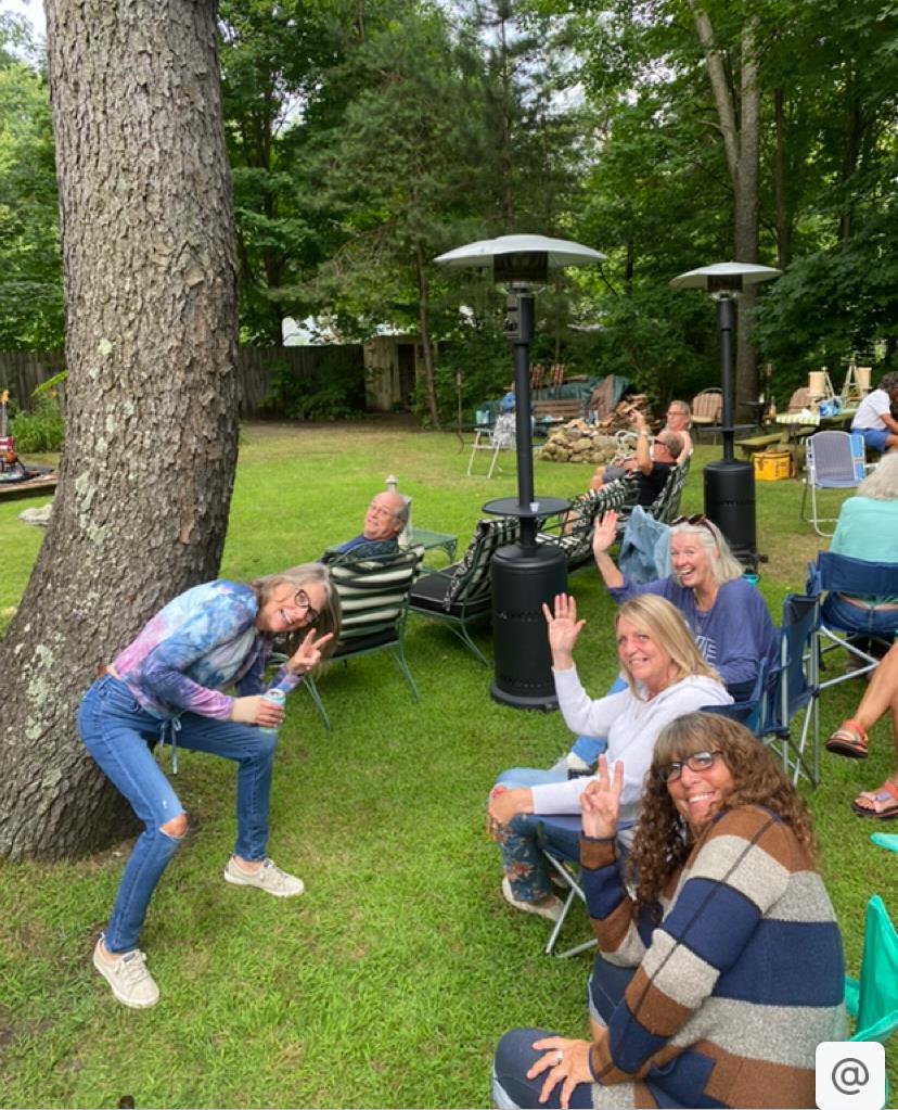 Group of friends socializing at a sunny outdoor event with laughter and smiles shared.