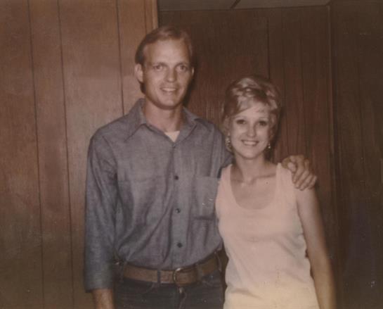 A man and woman smile, showing off their trendy 1970s outfits and hairstyles.