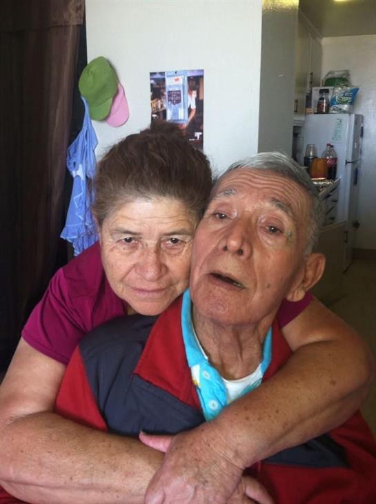An affectionate moment shared between an elderly couple inside their cozy home.