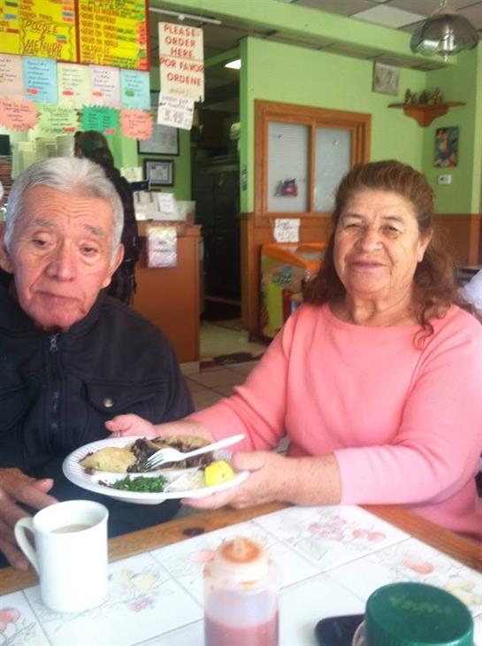 Two seniors share a meal at a restaurant, smiling and enjoying each other's company.